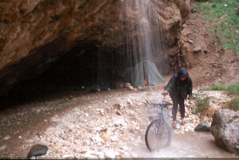 Washing bike in waterfall - tents placed in cave. 